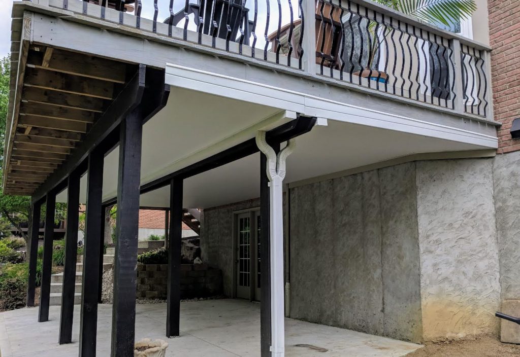 A porch with stairs and railing in the middle of it.
